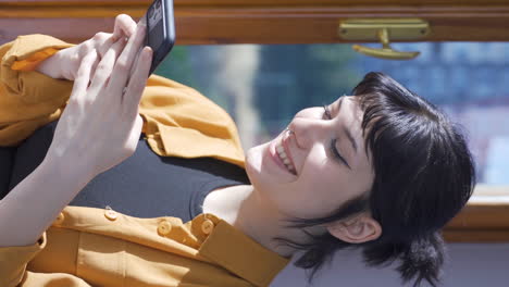 Vertical-video-of-Young-woman-smiling-at-phone-message.